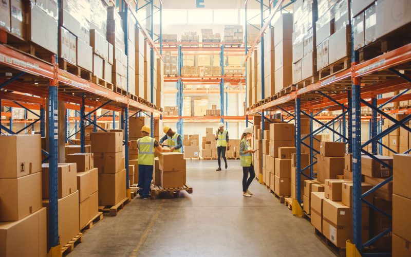 Retail Warehouse full of Shelves with Goods in Cardboard Boxes, Workers Scan and Sort Packages, Move Inventory with Pallet Trucks and Forklifts. Product Distribution Delivery Center.